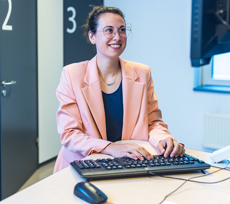 Sociaal verpleegkundige kijkt lachend naar haar scherm en typt