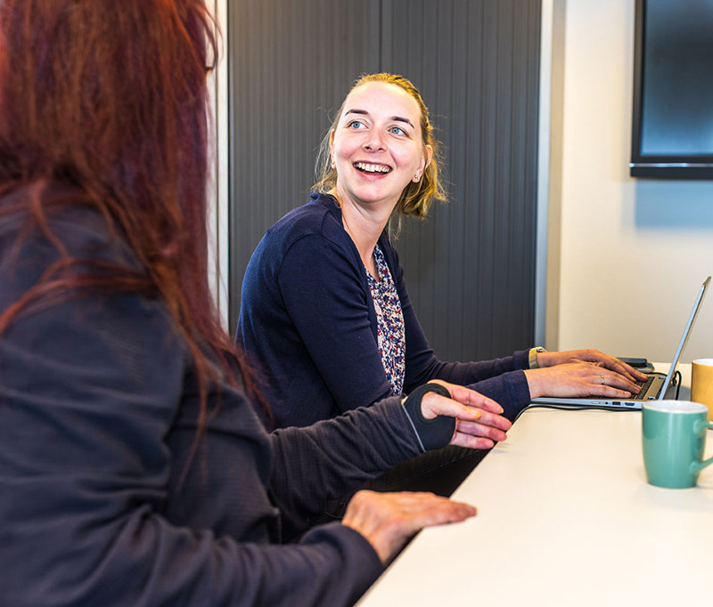 Arts Lacht Naar Collega En Werkt Achter Laptop Header