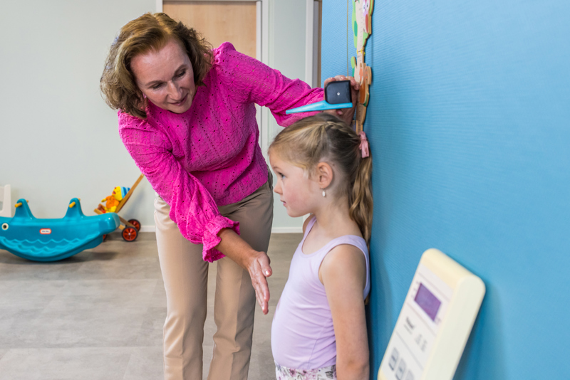 Een medewerker op het consultatiebureau meet kind