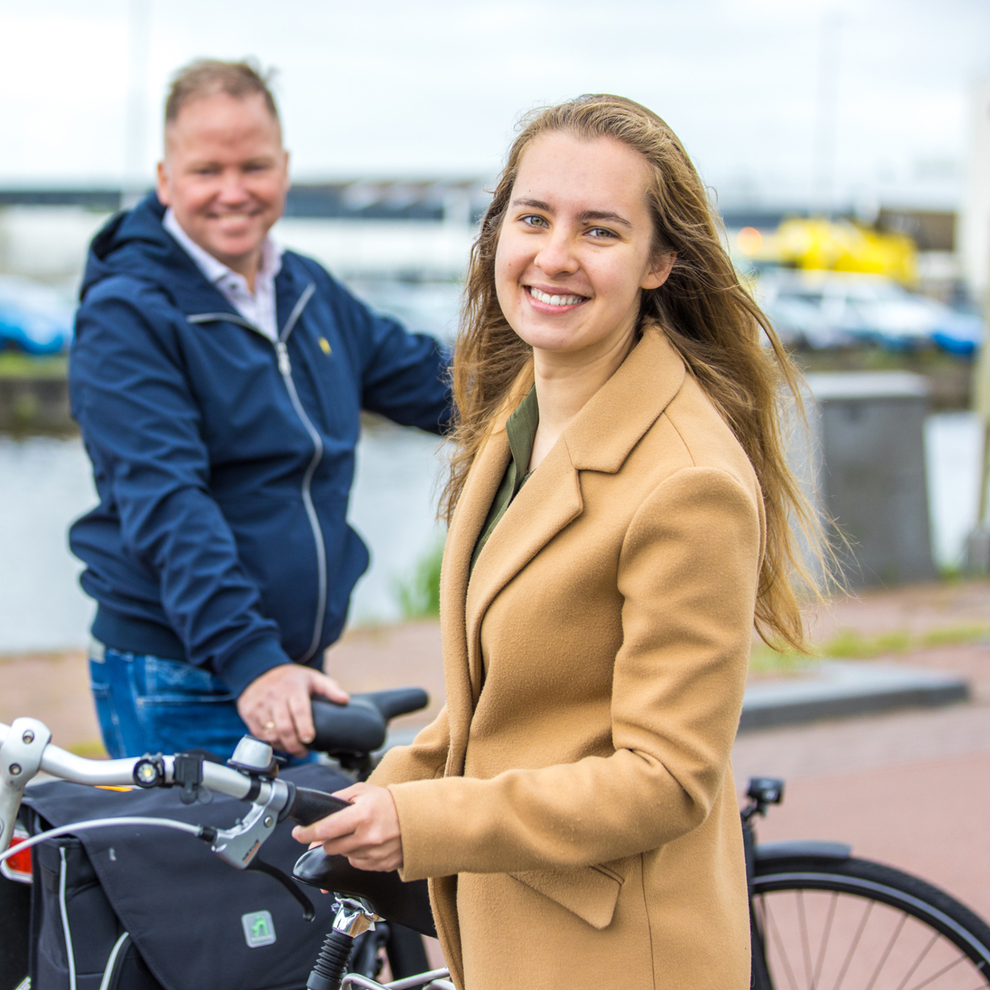 Twee personen met een fiets bij het water: Bij GGD Fryslân krijg je een individueel keuzebudget welke je bijvoorbeeld kunt gebruiken voor een fiets. 
